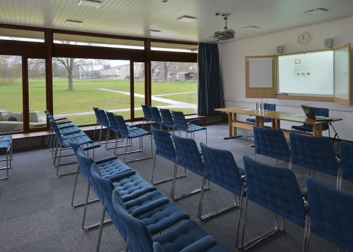 Situated off the Wolfson Hall foyer, this room can be used in conjunction with the theatre as a breakout space or in its own right as a meeting room. The wall of windows with inspiring views across the grounds gives a sense of tranquillity, whilst plentiful daylight helps to illuminate the room which is equipped with an "AV wall" to facilitate seamless presentations as well as free WiFi access.