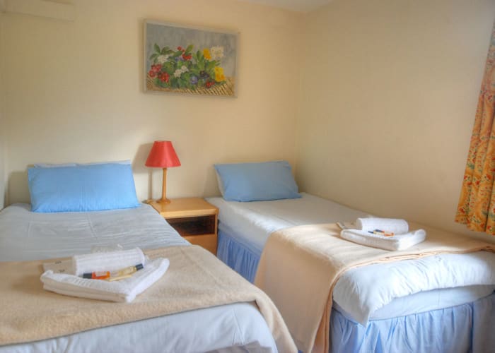 Twin bedroom with en suite bathroom and desk and seating area, with fridge and tea and coffee making facilities