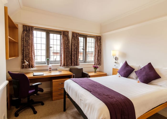 A double bedroom at Westminster College, two windows allow ample light into the room, chair, desk and double bed make this a great option for conference accommodation.