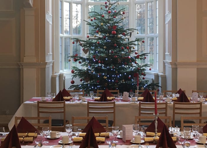 College Hall set up for festive dining experience with a Christmas tree in the background