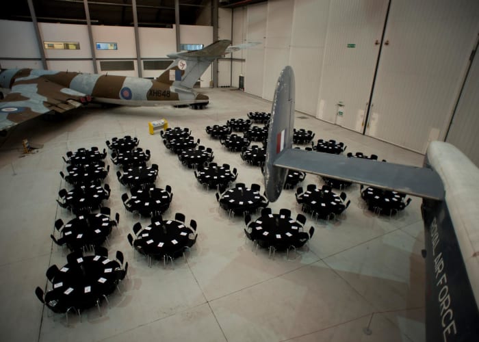 Aerial view of the Conservation Hall at IWM Duxford, set-up for delegates to have a dining experience under the wing of a plane