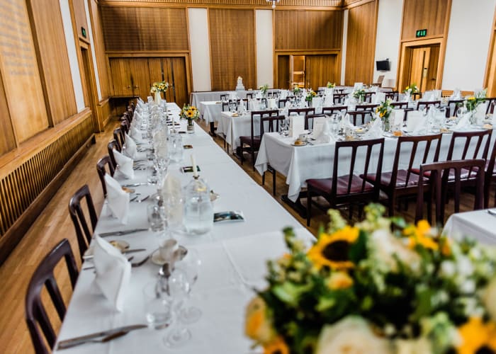 Wolfson College Dining Hall decorated with traditional wedding dÃ©cor, including white linen, place settings and flowers.