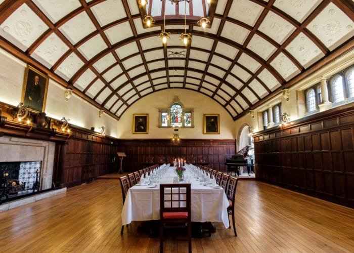 The beautiful dining hall at Westminster College, with oak-panelled walls, stained glass windows and cupola ceiling.