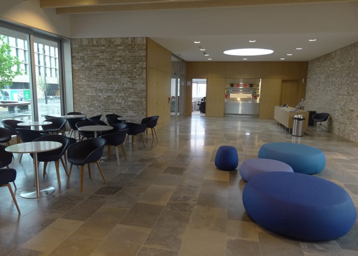 A large light open foyer area with blue beanbag seating, tables and chairs ideal for room hire.