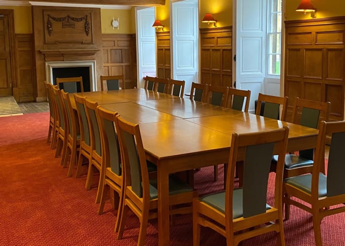 A grand paneled wall room with fire place mantle in a boardroom layout. An ideal setting for private dining.