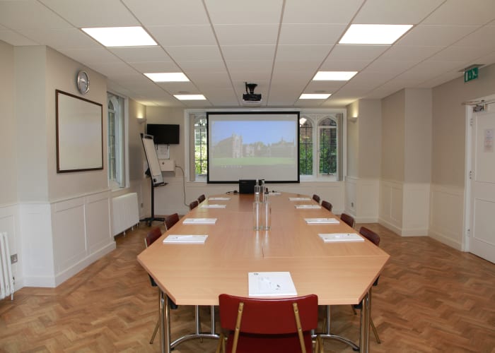 The Walters Room, complete with table and chairs, a large screen and projector, an ideal meeting room.