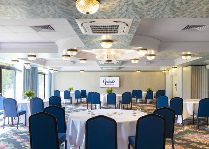 Lower Granta - Cabaret layout with white linen cloths, blue uniform chairs, a tv screen and views of the hotel gardens