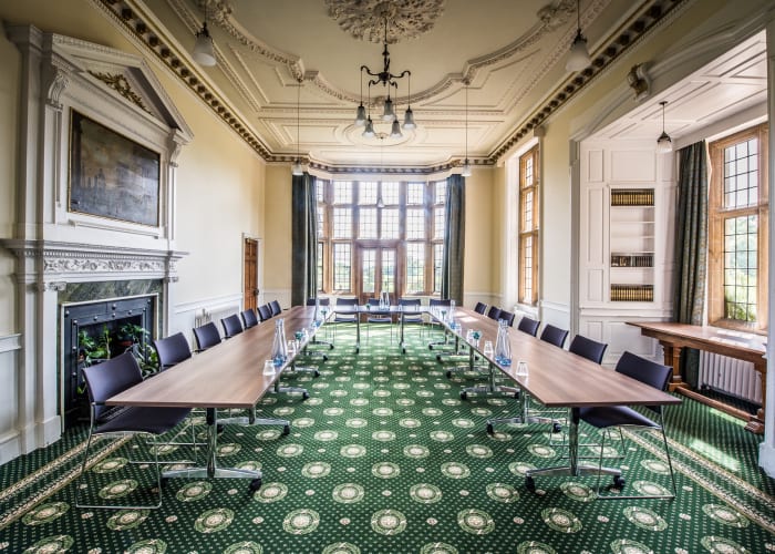 Traditional room with a historic fire place, floor to ceiling windows and dark green carpets to complete the room. This bright and open room is a very flexible event space