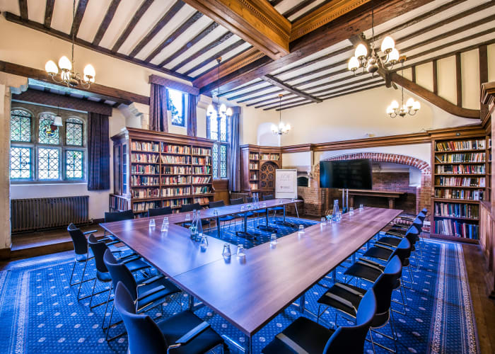 Stuart room - U-Shaped seating layout which can seat up to 16 delegates. Wooden beamed ceiling and multiple wooden bookcases.