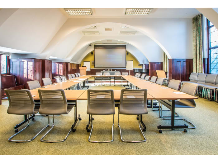 Impressive meeting room in Cambridge, long room, set a hollow boardroom style with chair all the way around, white curved ceiling and screen at the top of the room