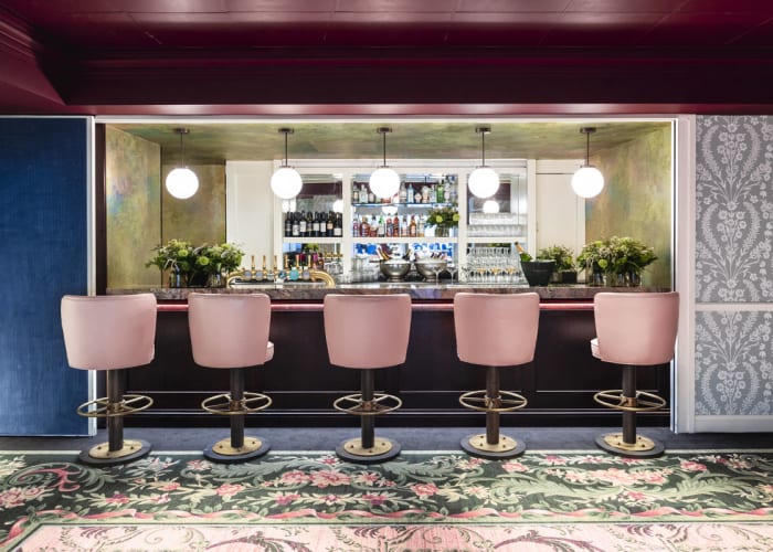 Rhee - Five pink bar stools, alongside the bar, plenty of natural lighting and space. Ideal for meetings or reception.