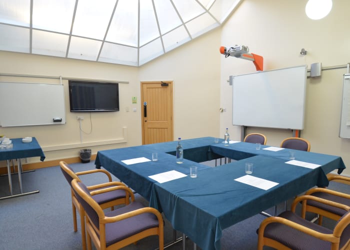 A small meeting room set boardroom style with a whiteboard and TV, ideal for private meetings and interviews.