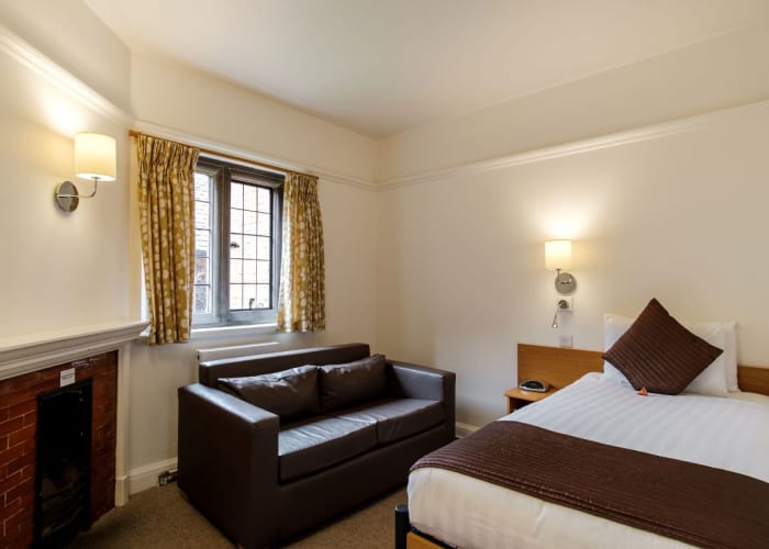 Single Suite at Westminster College with bed, bedside unit, sofa and fire place in the corner. Great accommodation for conference guests.