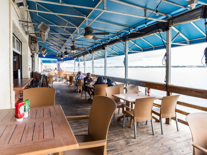 People having a meal on the outdoor waterfront deck at Backwater's on Sand Key