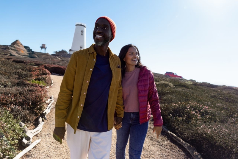 Couple walking along path with Piedras Blancas Light Station in background