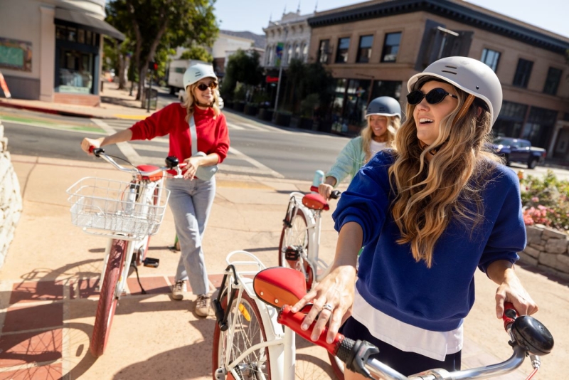 Three people in helmets walking with bikes in Mission Plaza San Luis Obispo, CA