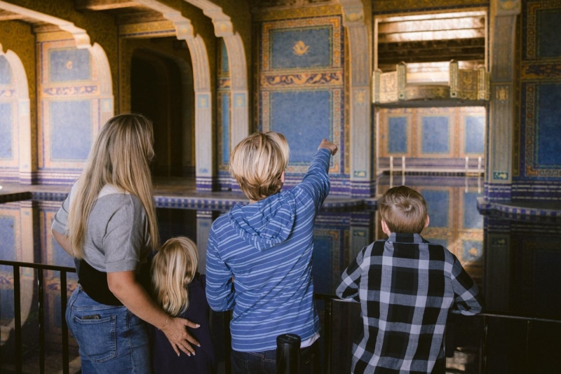 Adult and three children looking at the blue roman indoor pool at Hearst Castle