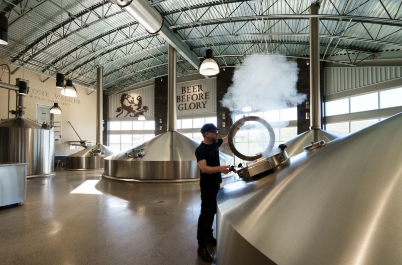 Brewmaster opening fermentation tank in a Firestone Walker Brewery with steam coming out