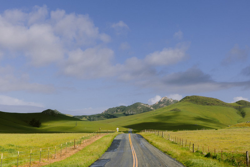 Empty road leading to green hills