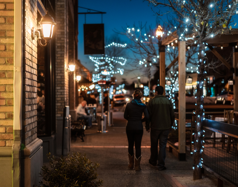 Couple walking down sidewalk in the Arroyo Grande Village with twinkle lights in the trees