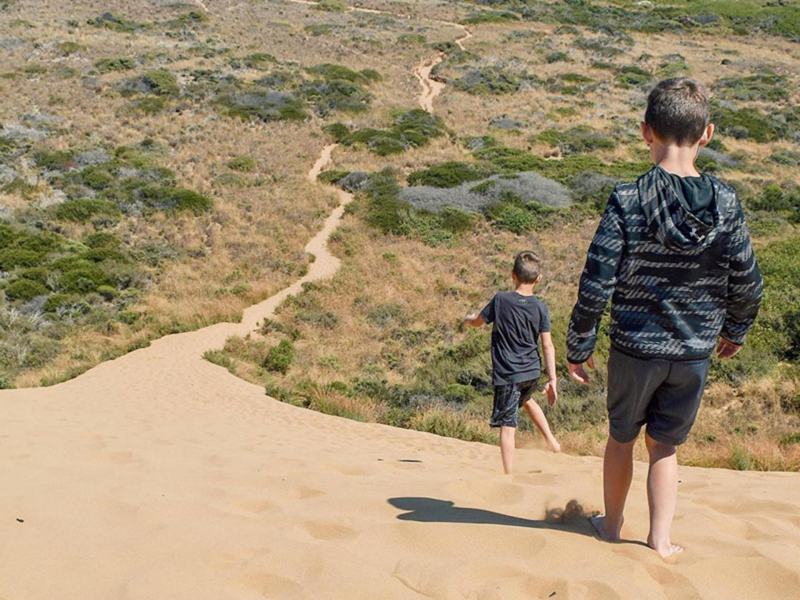 Two kids hiking down a sandy path at Harmony Headlands Park in SLO CAL