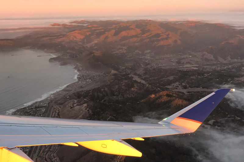 Horizon view of the coast at sunrise with plane wing in foreground