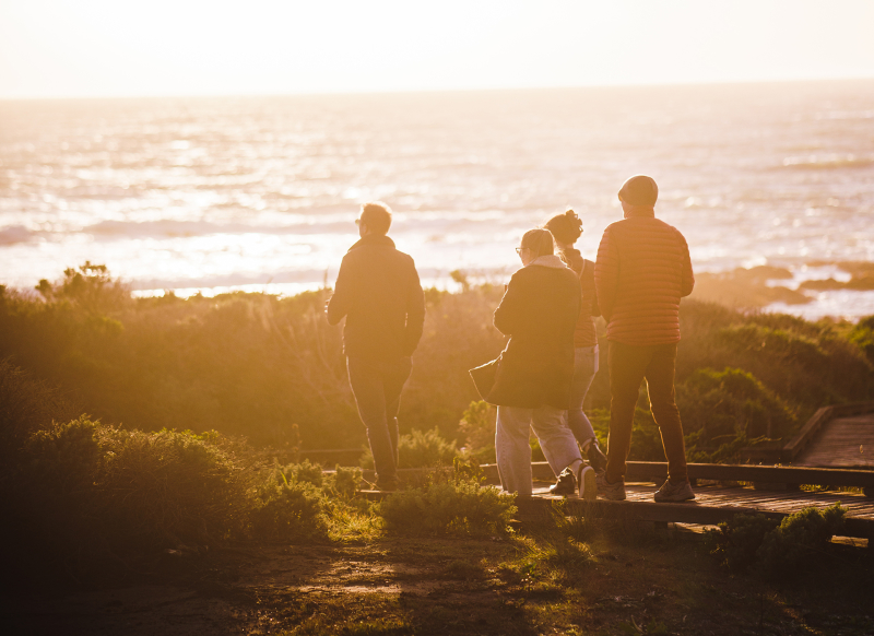 Group walking on an oceanfront boardwalk at sunset
