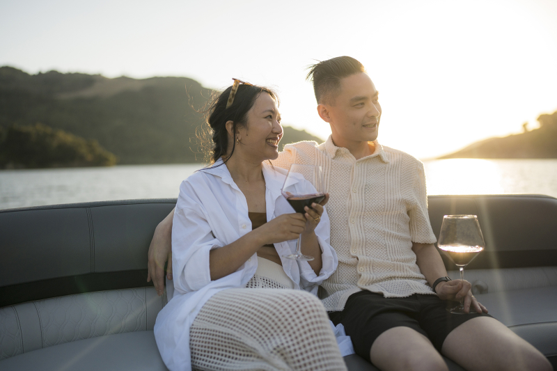 Couple drinking wine on a boat with lake in background