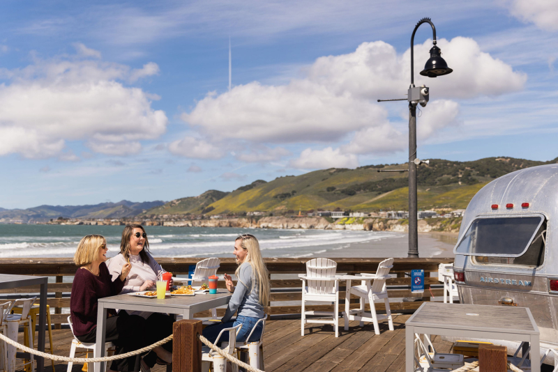 three women dining at a table on the pismo beach pier