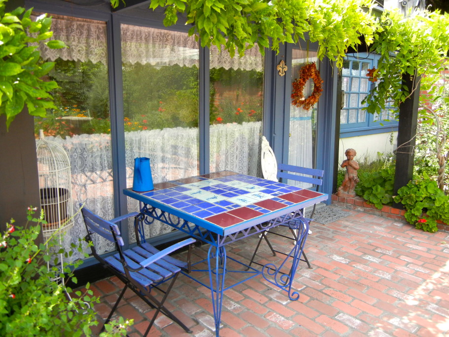 Table & chairs under wisteria overhang.