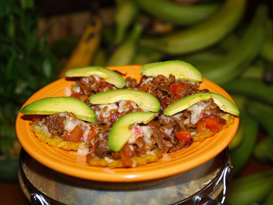 Tostones Con Carne ( Rockystyle) Fried Green Plantains topped with steak, avocado, tomatoes, onions,
