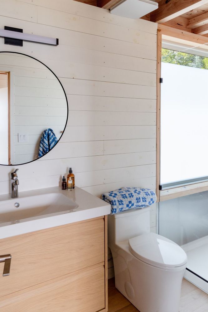 Minimalist cabin bathroom detailing clean lines, local timber features, and modern fixtures.