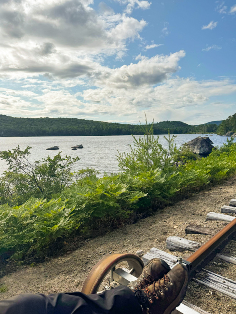 A rail biker rider glides along the tracks next to a lake.