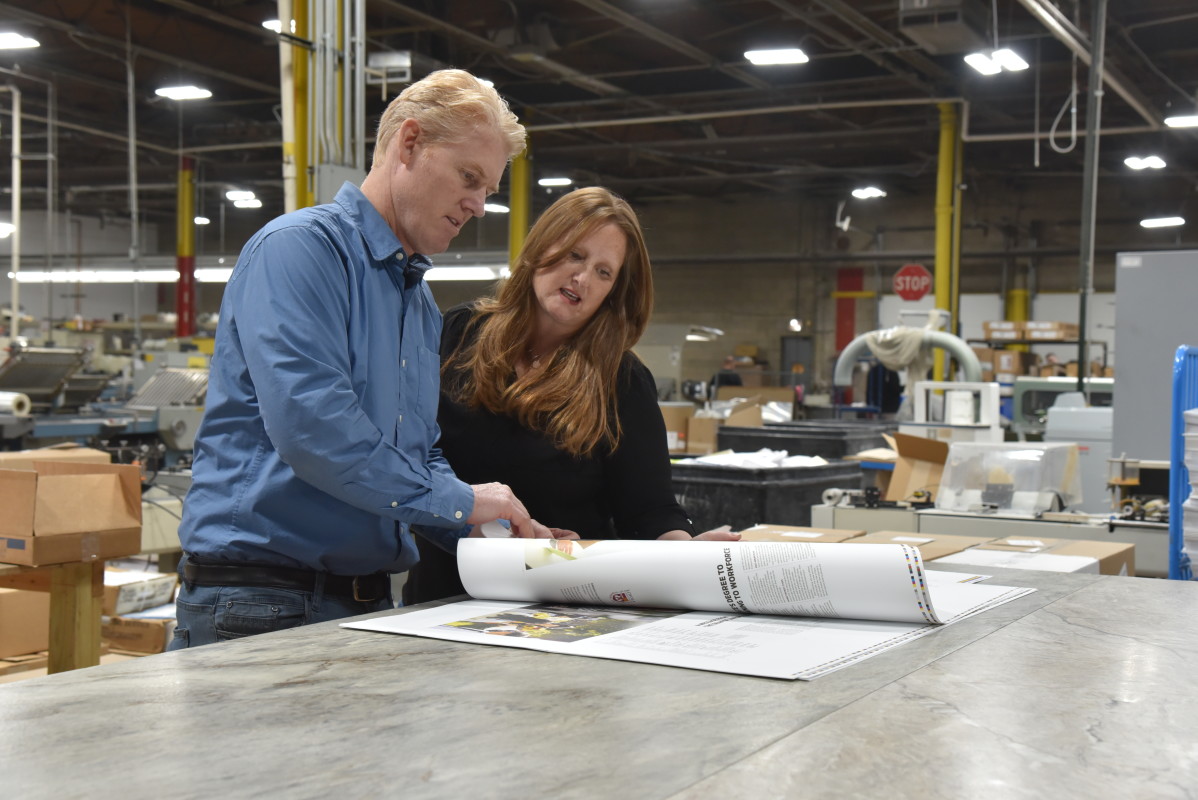 Managing Partners, Angie and Bob, carefully inspecting a press sheet for quality