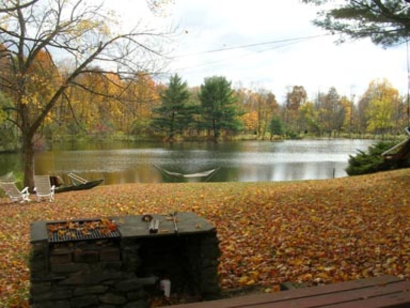                        The stone barbecue and hammock by the lake at the Hudson Valley Cabin on a fall day.
                        