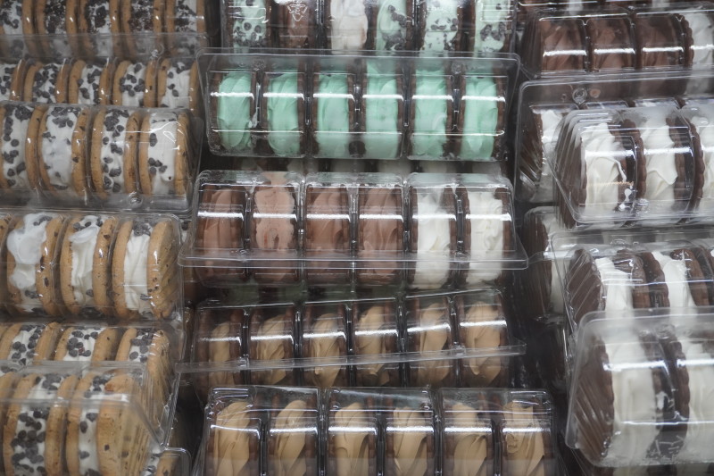                         A freezer is full of assorted ice cream sandwiches for sale.
                        