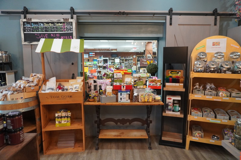                         Display stands filled with fun shopping finds and a window peeking into the wine shop next door
                        
