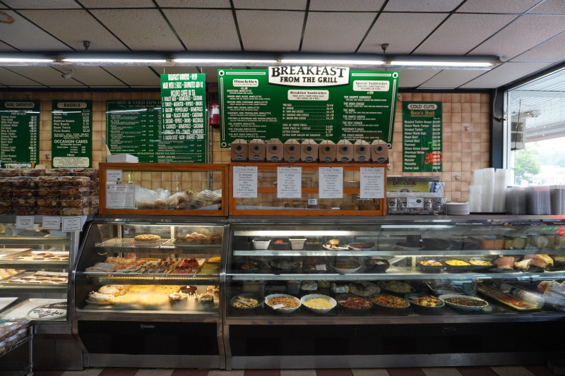                         A sign shows off an extension breakfast menu, and there is a refrigerator full of different spreads, salads, and more!
                        