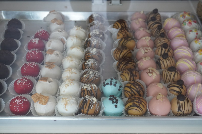                         Colorful assorted cake pops in a display case
                        