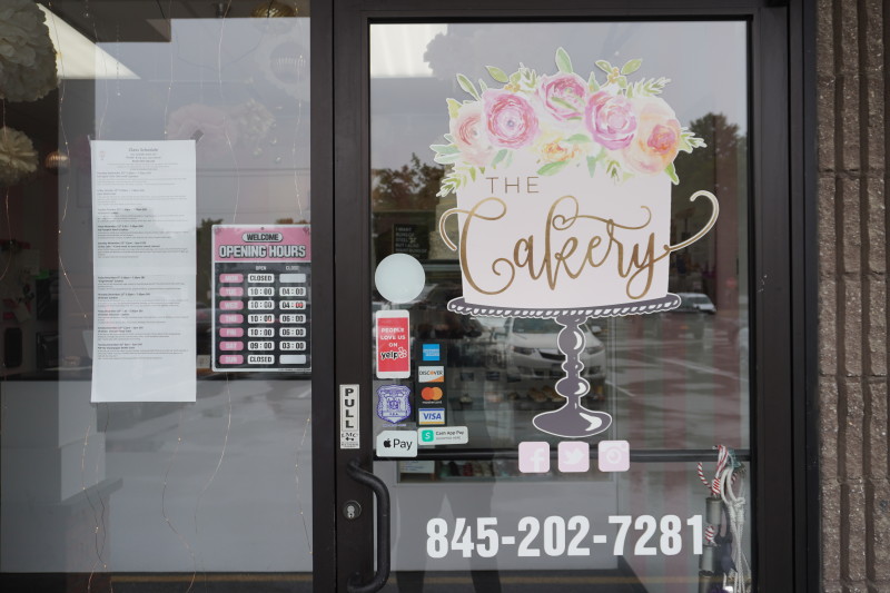                         Exterior of The Cakery with the door and logo showing
                        