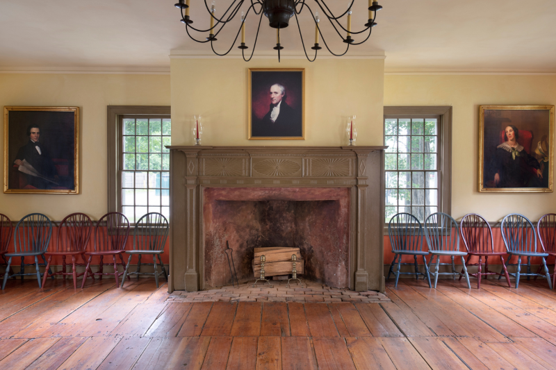                         Medium sized room with a large fireplace, painted portraits, and chairs.
                        