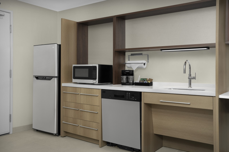                         The kitchen in one of the rooms at Home2 Suites, including a refrigerator, a dishwasher, a countertop and a sink.
                        