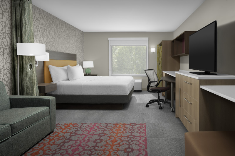                         One of the rooms at Home2 Suites, complete with one bed, a couch, a flat-screen TV, and a desk.
                        