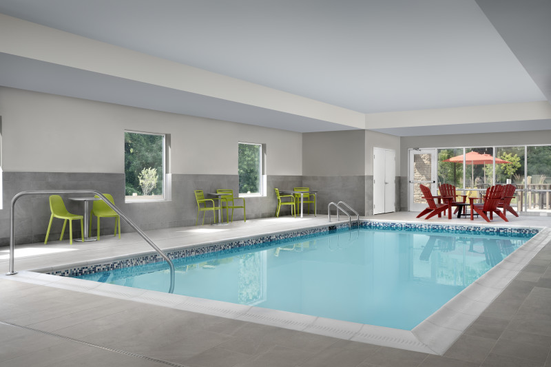                         The indoor pool at Home2 Suites with pool furniture on the pool deck.
                        