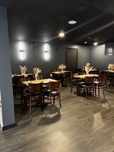                 The interior of Coco Bella Restaurant, with gray walls and wood tables and chairs.
                