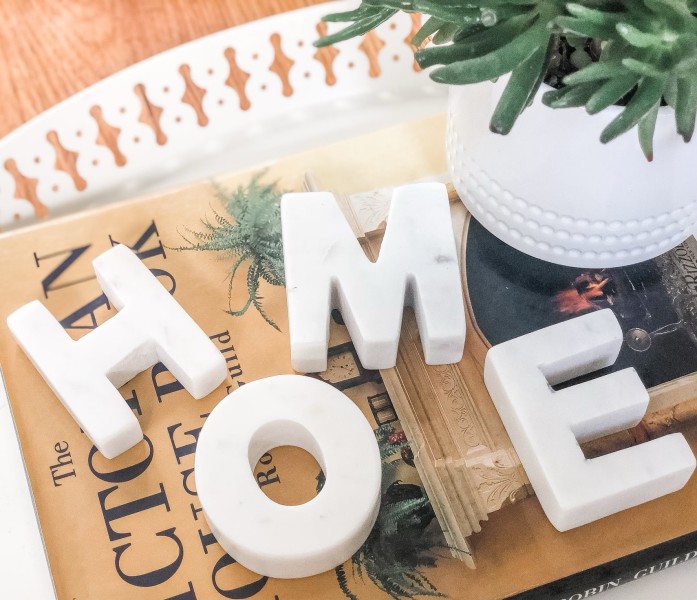                         A decorative display on a table with the letters H O M E carved out of heavy looking pieces of white marble.
                        