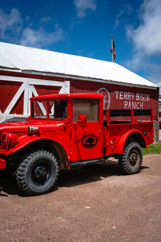 A red antique pickup truck next to a red barn