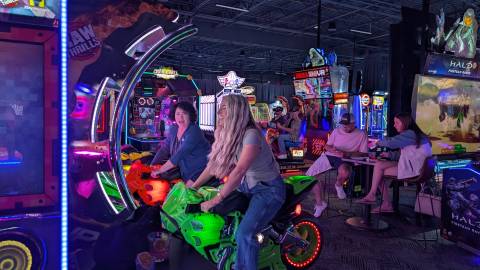 People having fun riding arcade bikes at Dave & Buster's