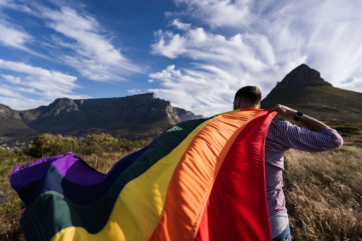 https://assets.simpleviewinc.com/simpleview/image/upload/c_limit,h_1200,q_75,w_1200/v1/clients/iglta/Man_Waving_LGBT_Flag_with_Table_Mountain_in_the_Background_dd0066ef-5066-465d-9d6e-45edf1943afa.jpg