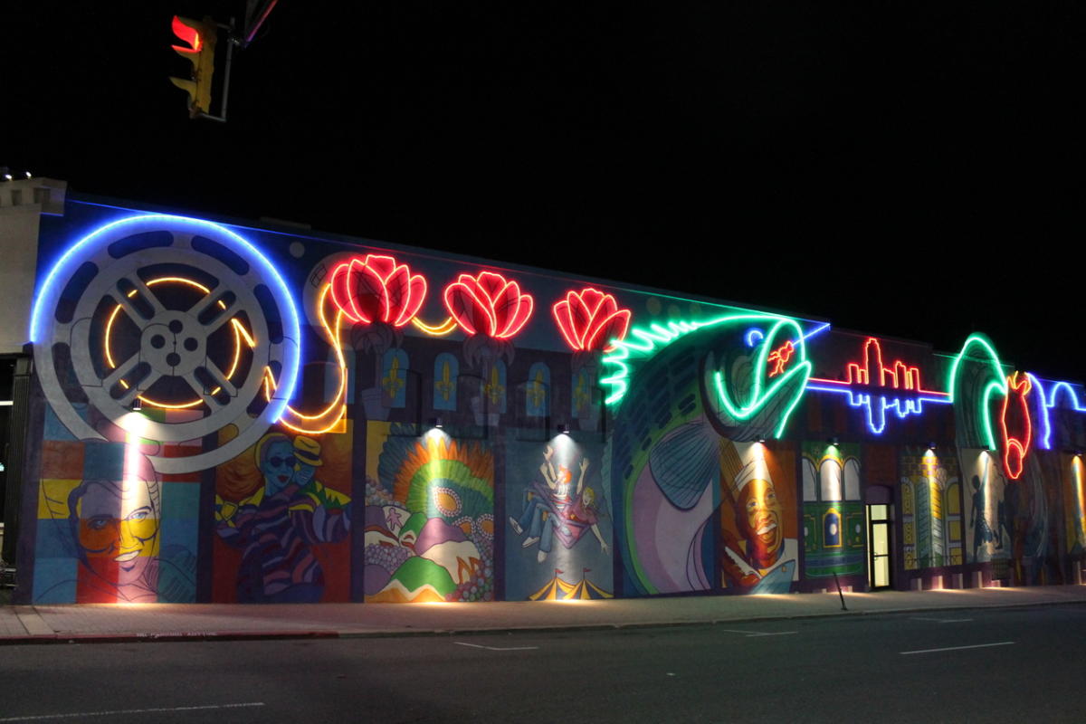A vibrant neon-lit mural featuring diverse figures and symbols